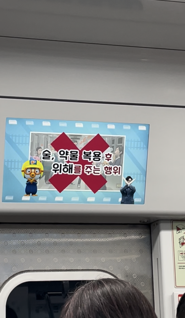 韓国の地下鉄の中のディスプレイ。手話通訳者が大きく手をバツの形にしている