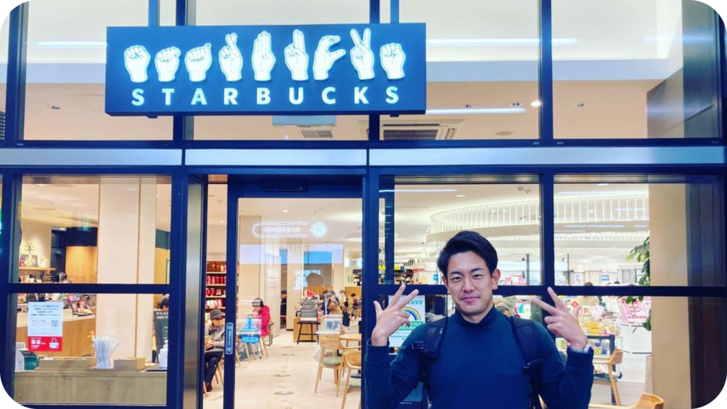 国内唯一のサイニングスタバである国立nonowa店の店の前で、STARBUCKSと指文字で表示されている看板と記念に写真撮影。野寺選手は「スタバ」の手話を表出。